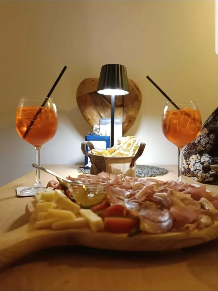 Due calici e un tagliere di salumi e formaggi con la lampada accesa sul tavolo, di sera