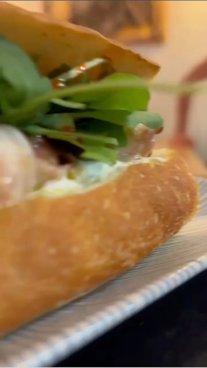 Un panino imbottito con formaggio fresco e foglie di rucola, visto da vicino