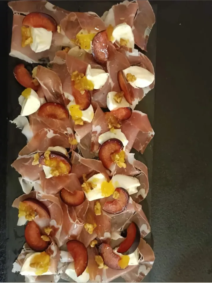 Un lungo vassoio scuro di tartine con prosciutto crudo, uovo e olive